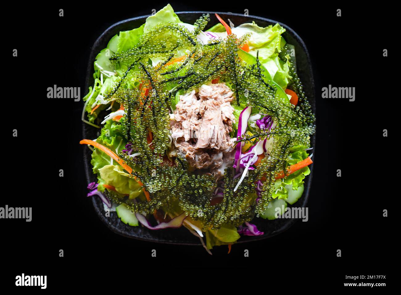 Salade vietnamienne fraîche avec légumes, thon et raisin de mer sur fond noir vue de dessus Banque D'Images