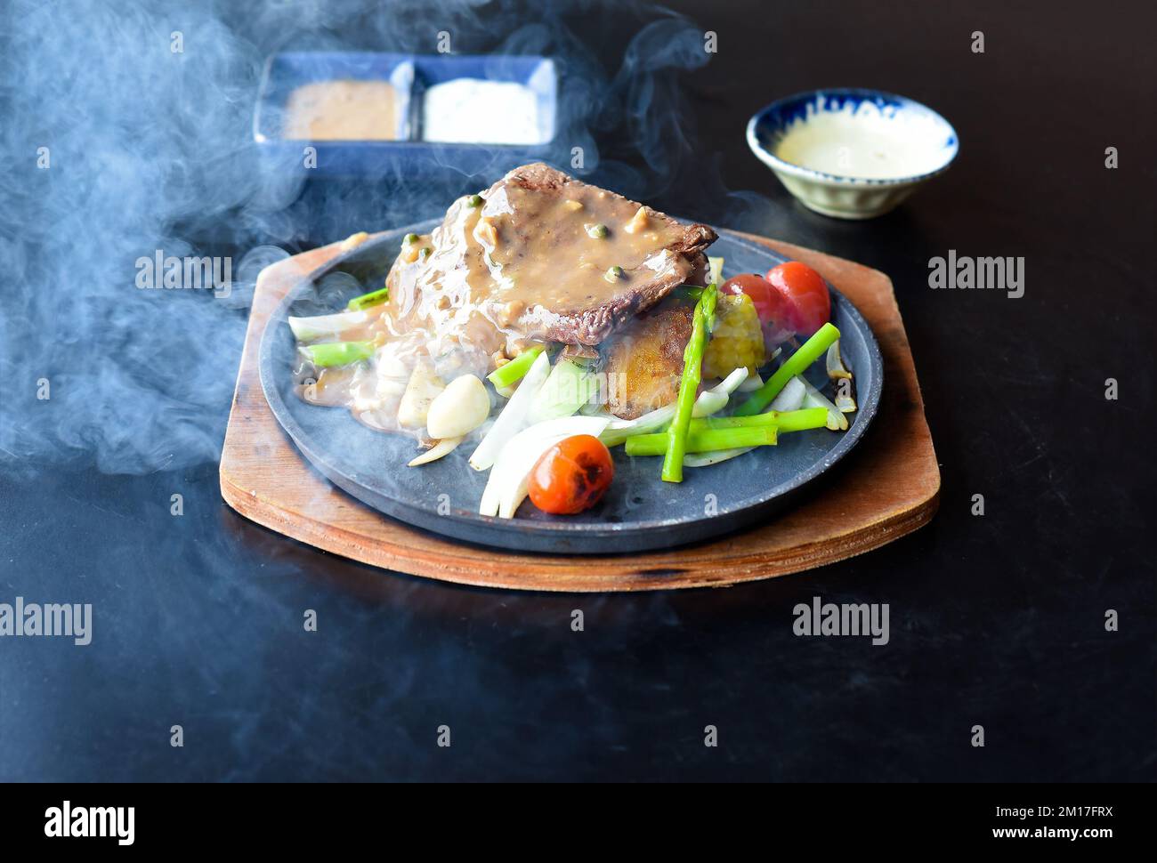 Steak de bœuf grillé avec légumes et légumes verts sur l'assiette isolée sur fond noir vue latérale Banque D'Images