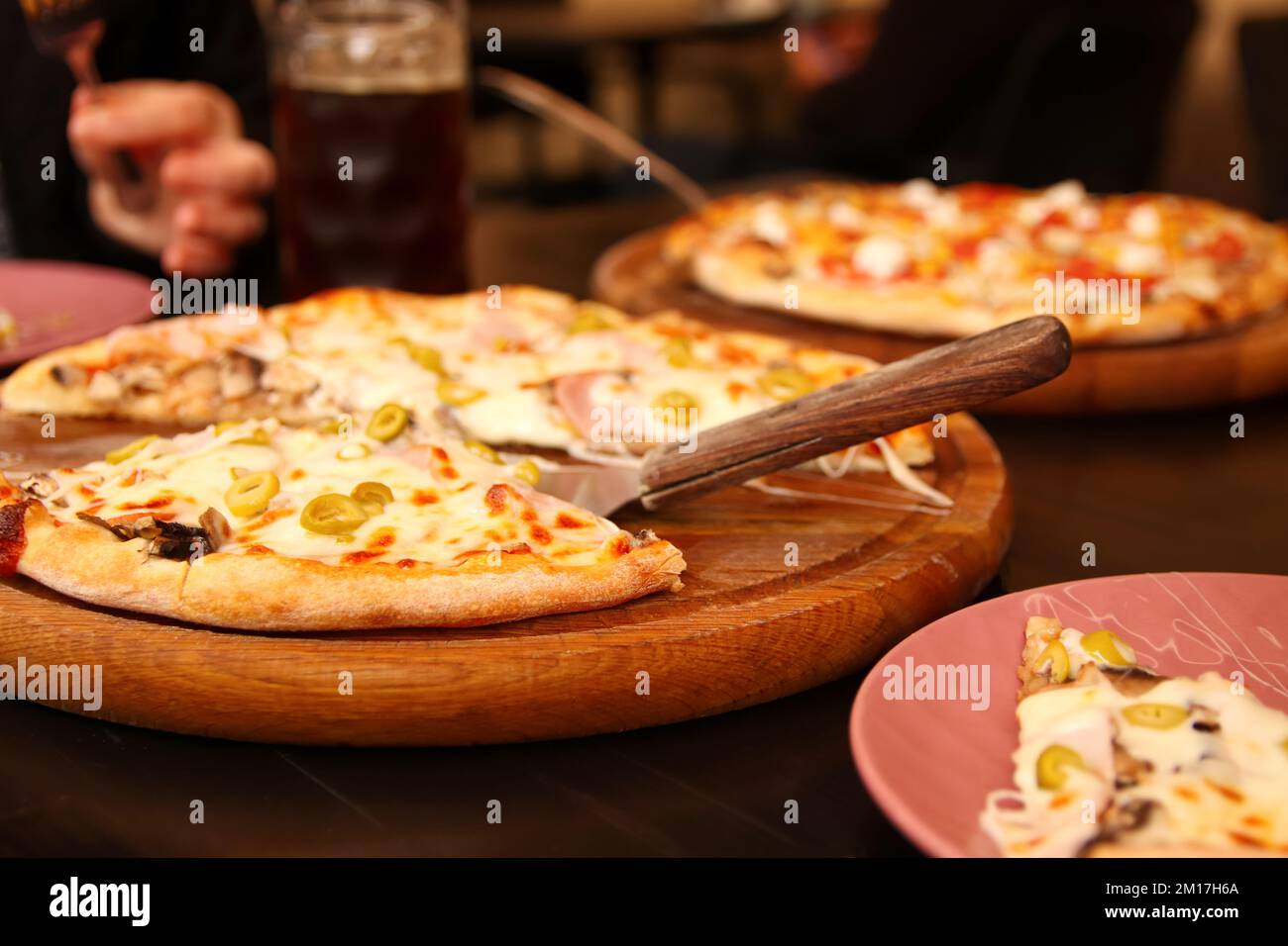 Refocalisation sur le fond de la pizza italienne avec des olives vertes sur la table. Tortilla avec mozzarella râpée. Pizza aux olives, basilic et fromage en gros plan Banque D'Images