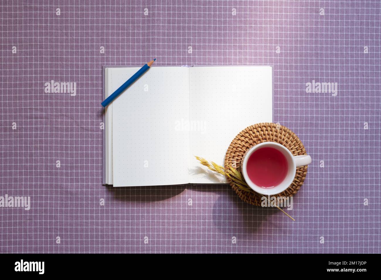 Ouvrez le carnet et le crayon de couleur, tasse de thé noir sur fond de tissu violet à carreaux. vue de dessus, espace de copie Banque D'Images