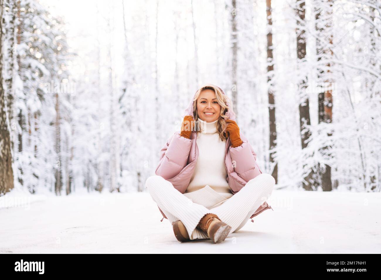 Portrait d'une femme blonde souriante aux cheveux blonds vêtu d'hiver dans une forêt enneigée d'hiver Banque D'Images