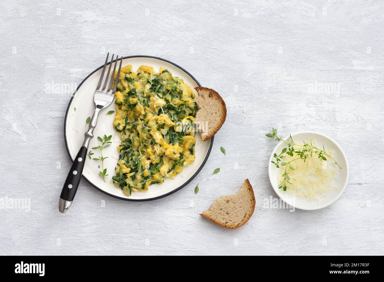 Scrumble œufs avec kale et fromage sur fond gris clair, vue du dessus. délicieux petit déjeuner maison Banque D'Images