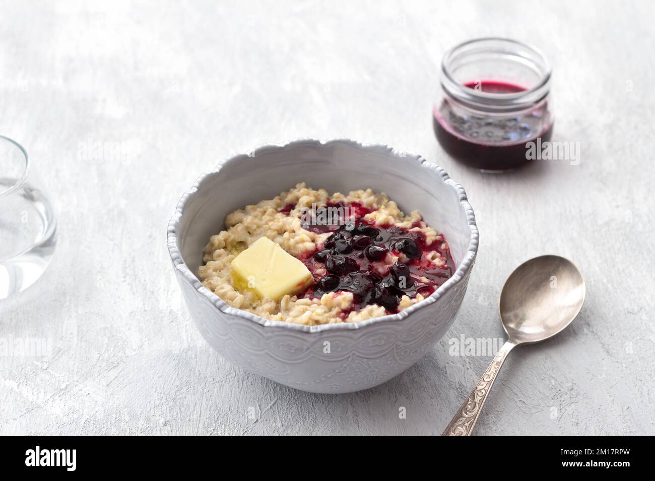 Délicieux porridge de flocons d'avoine avec beurre et confiture dans un bol gris sur fond gris clair. petit déjeuner maison sain. mise au point sélective, espace Banque D'Images