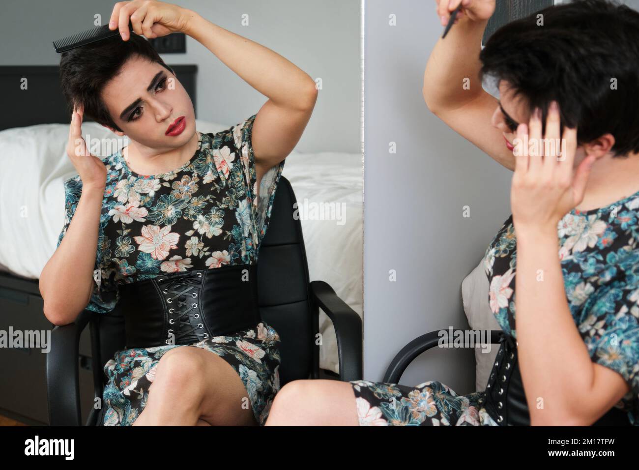 Jeune homme transgenre peignant ses cheveux devant le miroir. Banque D'Images