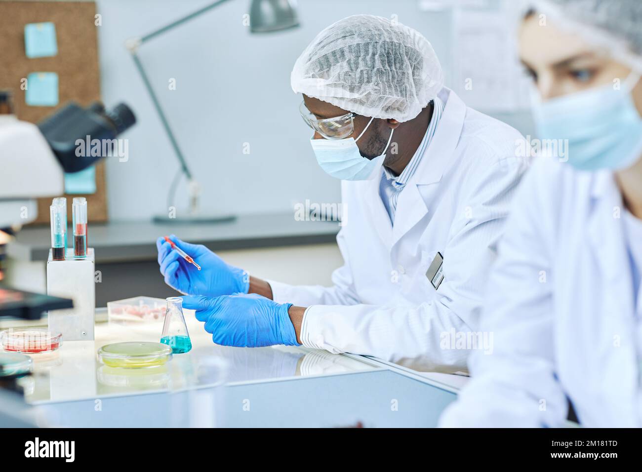 Vue latérale d'un homme noir travaillant dans un laboratoire moderne et effectuant des analyses de sang Banque D'Images