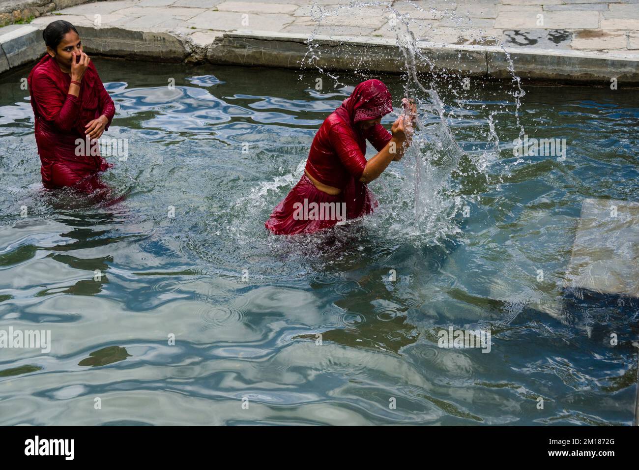 Deux femmes pèlerins ont une douche pour purifier le corps et l'âme en passant par le puits sainte 108 Banque D'Images