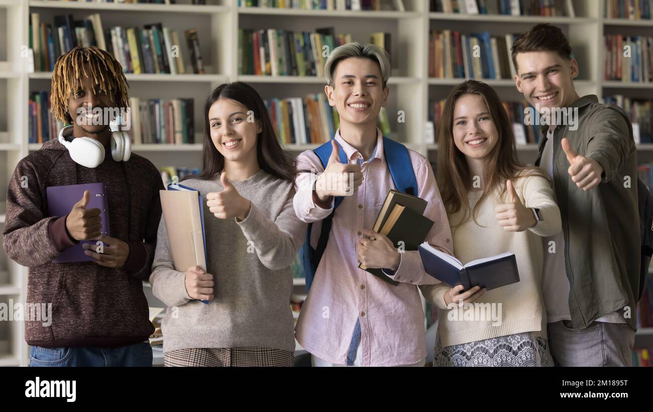 Heureux étudiants multiethniques de première année de collège posant dans la bibliothèque de l'université Banque D'Images
