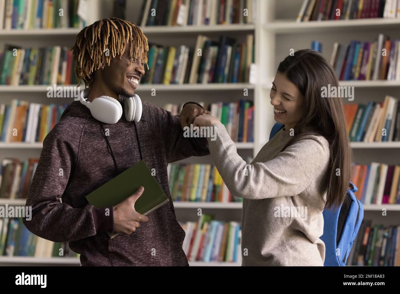 Joyeux deux étudiants divers, une fille et un gars se rencontrent dans la bibliothèque Banque D'Images