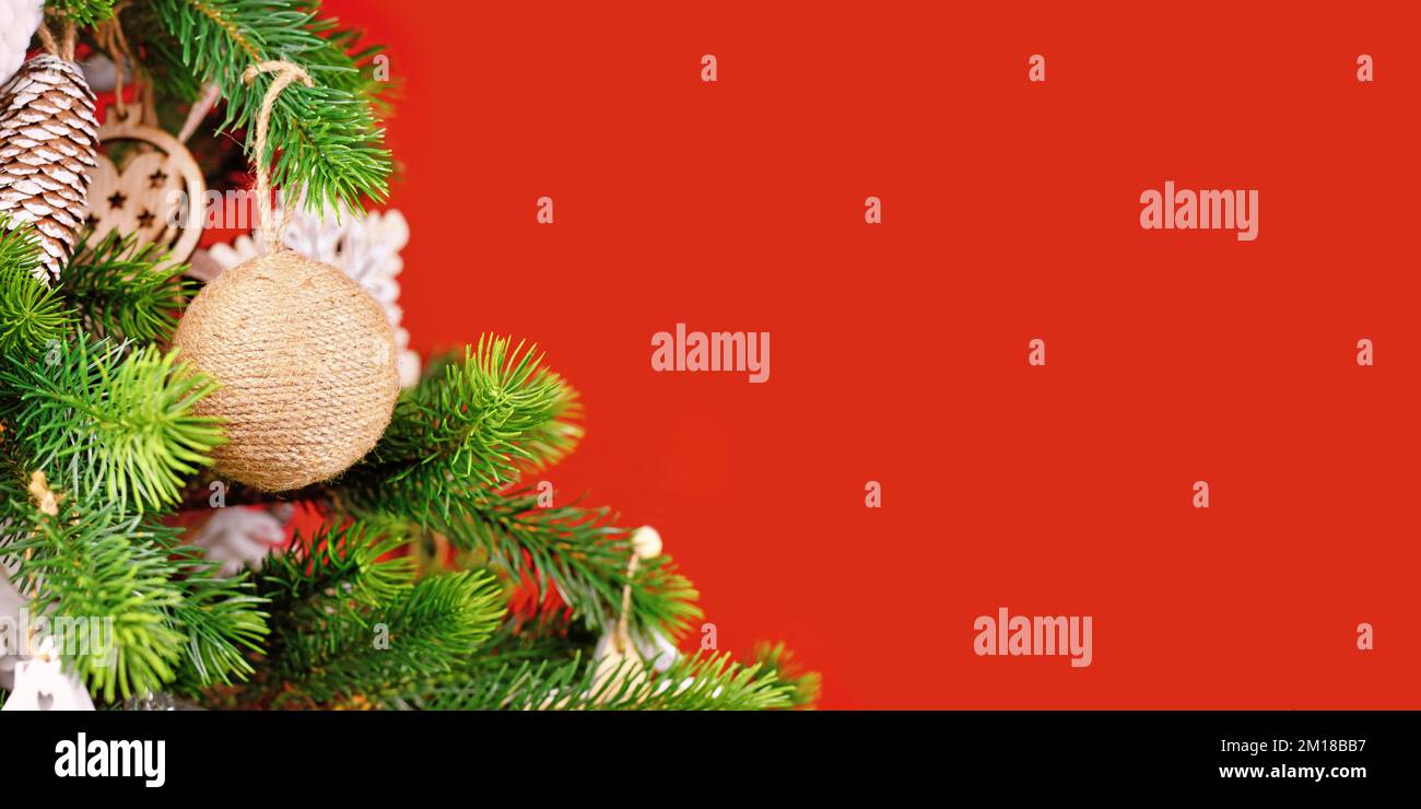 Bannière avec branches d'arbre de Noël avec boule décorative naturelle en corde de jute beige sur fond rouge Banque D'Images