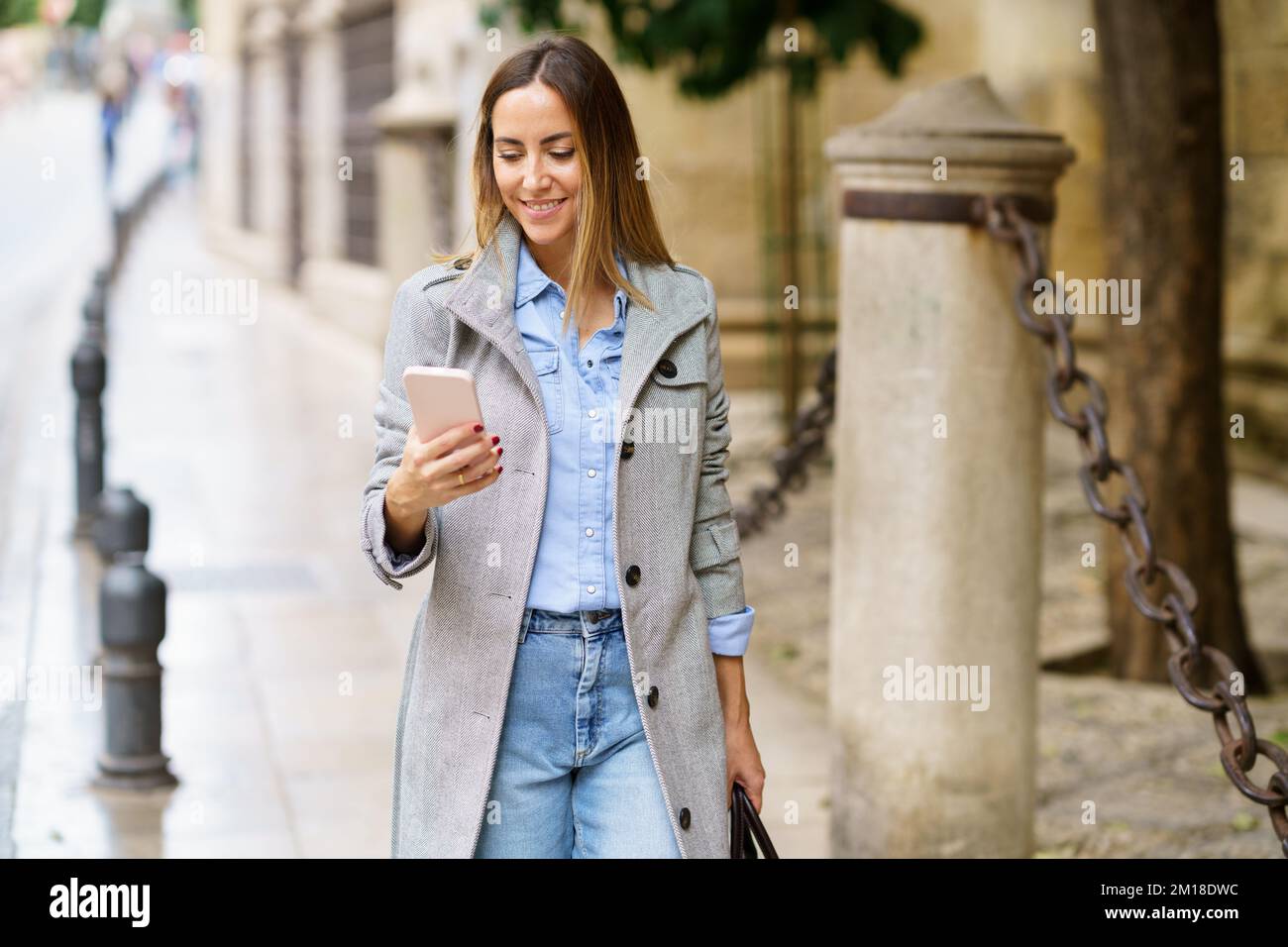 Femme lisant des messages sur un téléphone portable dans la rue Banque D'Images