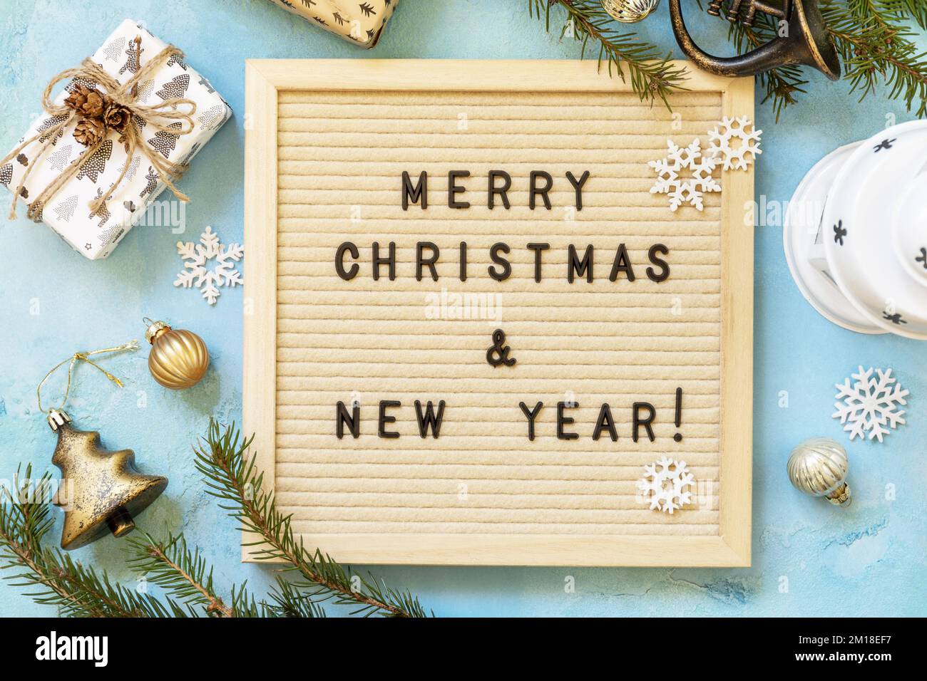 Cartes de vœux Joyeux Noël et joyeuses fêtes de la nouvelle année. Lettrage Joyeux Noël sur un tableau de lettres, boxes cadeaux et décorations dorées sur un dos bleu Banque D'Images