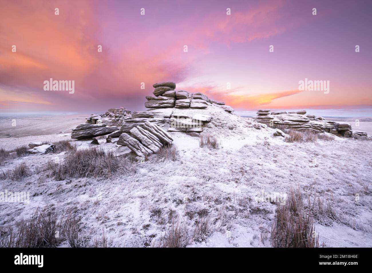 Merrivale, parc national de Dartmoor, Devon, Royaume-Uni. 11th décembre 2022. Météo au Royaume-Uni : feu et glace sur Dartmoor. Le ciel au lever du soleil brille d'orange contre la neige couverte par la grande porte de mis lors d'une matinée froide et hivernale. Les conditions hivernales devraient se poursuivre cette semaine avec d'autres prévisions de neige. Credit: Celia McMahon/Alamy Live News Banque D'Images