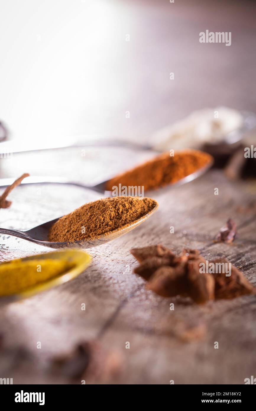Épices brésiliennes typiques - amandes, cannelle, paprika et poudre de curcuma dans une cuillère sur une table rustique en bois. Banque D'Images