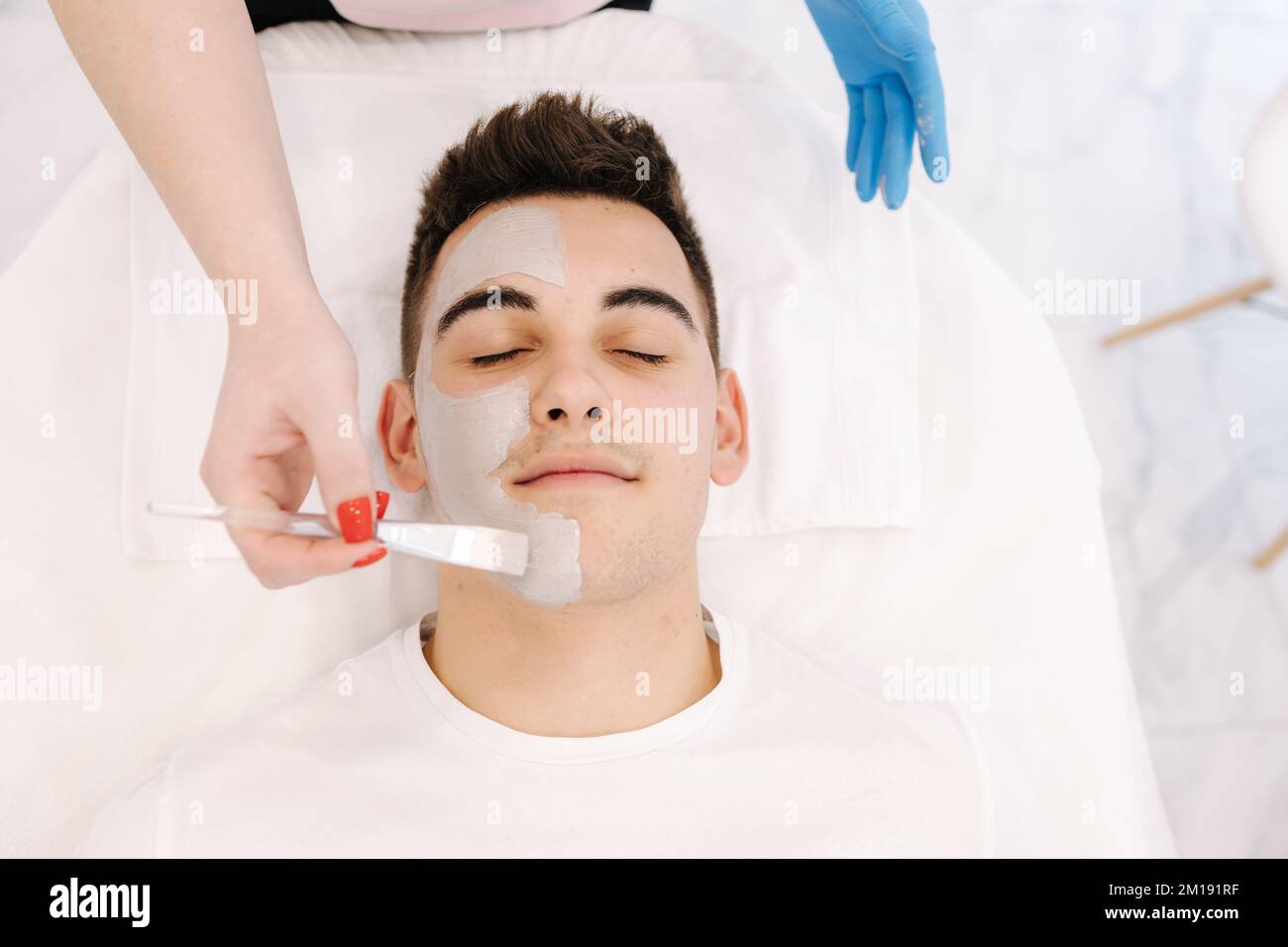 Vue de dessus de homme dans le salon de spa. Beau homme ayant un masque cosmétique dans le studio de beauté. Banque D'Images