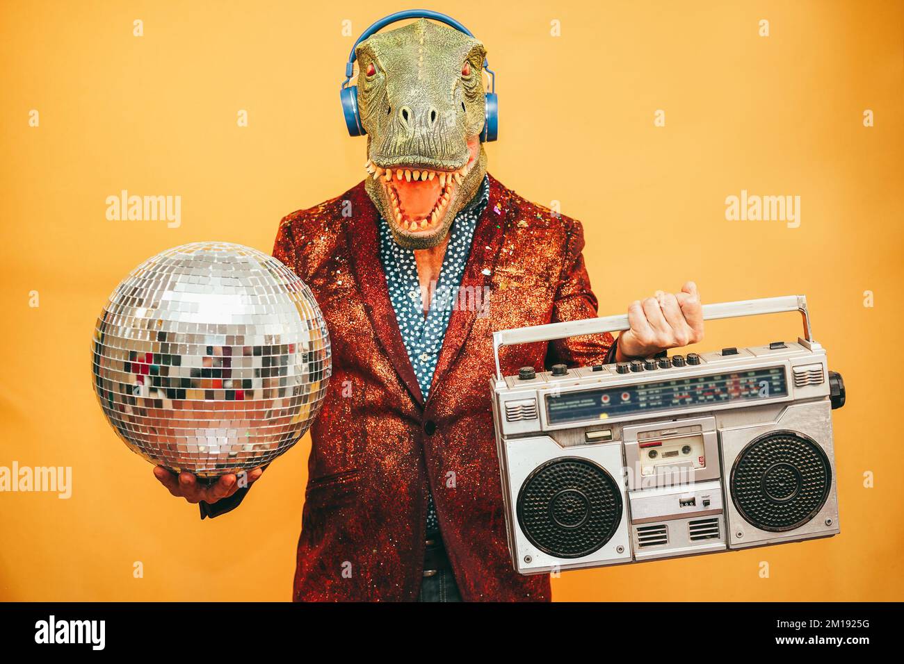 Fou portant un masque t-rex écoutant de la musique avec une stéréo boombox vintage pendant la veille du nouvel an - Focus sur le masque Banque D'Images