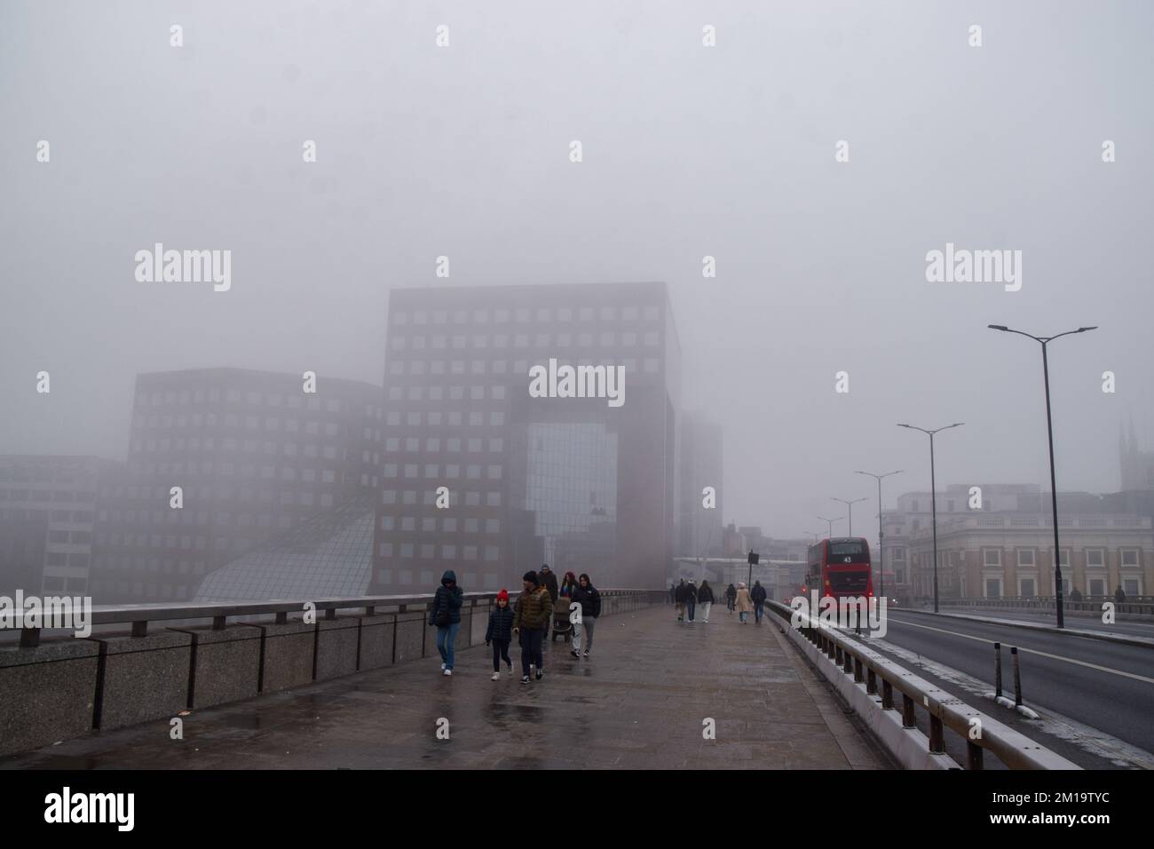 Londres, Royaume-Uni. 11th décembre 2022. Les gens marchent le long du London Bridge en passant par le bâtiment Shard, complètement obscurci par un épais brouillard. Londres s'est réveillée par le brouillard et les températures glaciales alors que le temps arctique de la Scandinavie, appelé Troll de Trondheim, a frappé le Royaume-Uni. Banque D'Images