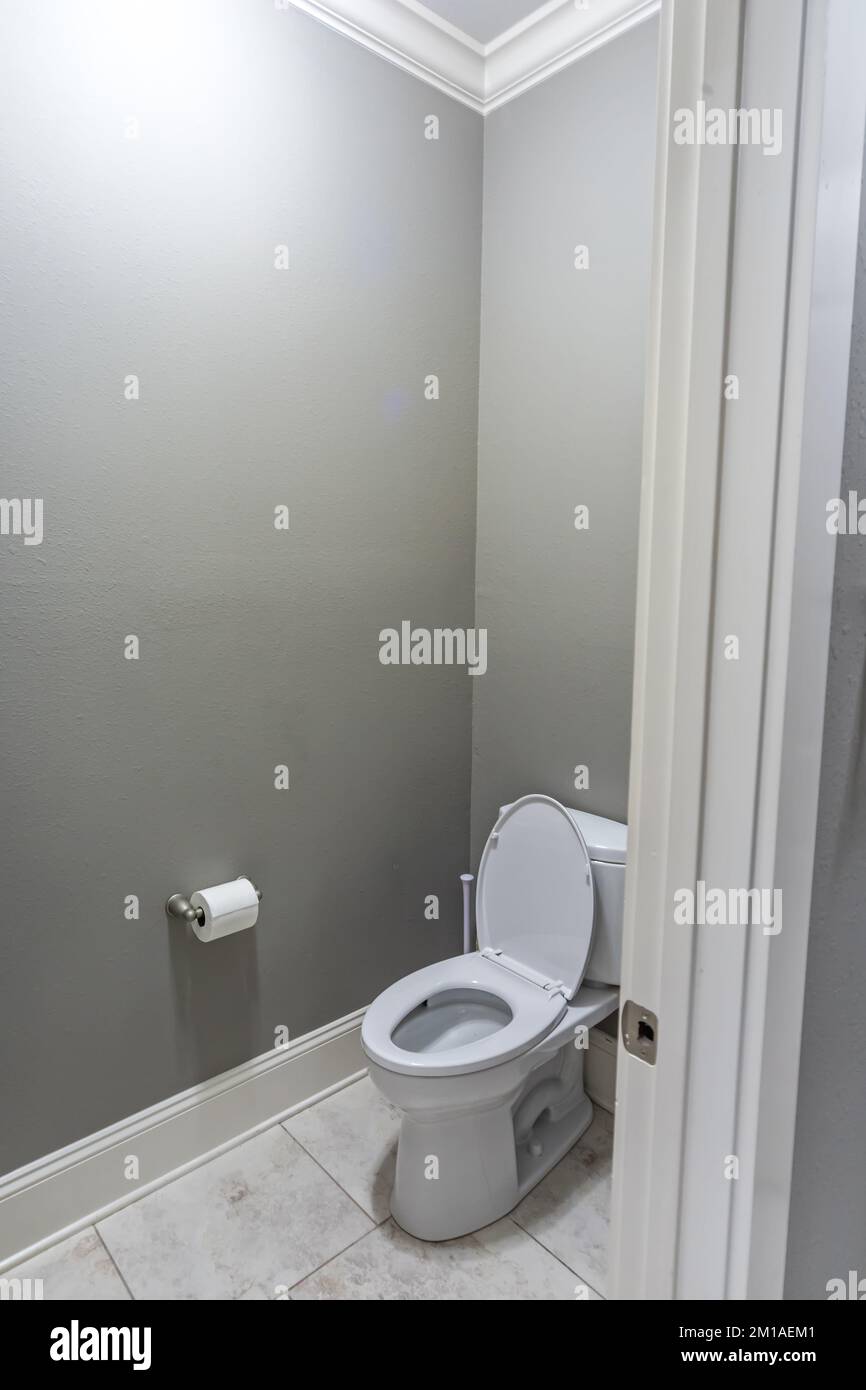 Une petite salle de bains avec des murs gris et des toilettes avec des sols carrelés dans une nouvelle maison de construction Banque D'Images