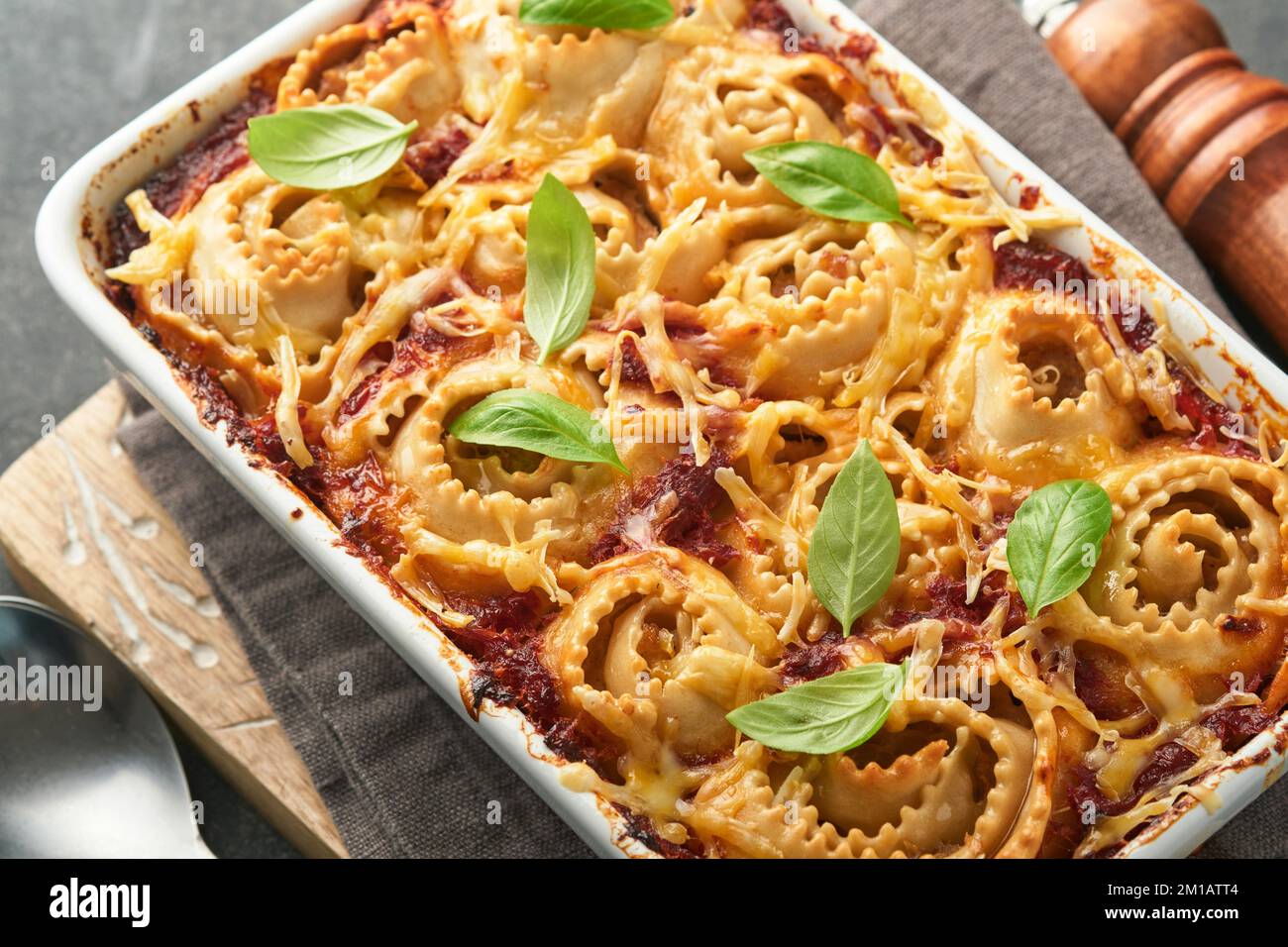 Lasagnes. Pâtes de lasagne faites maison rotolo cuire avec sauce tomate, fromage à la crème et basilic sur une poêle blanche sur fond d'ardoise sombre, de pierre ou de béton. Il Banque D'Images