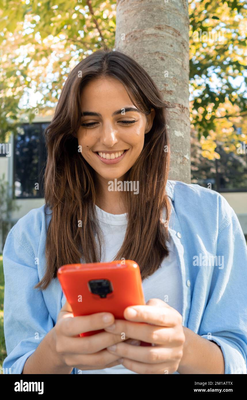 Jeune femme souriante discutant avec un smartphone dans un parc Banque D'Images
