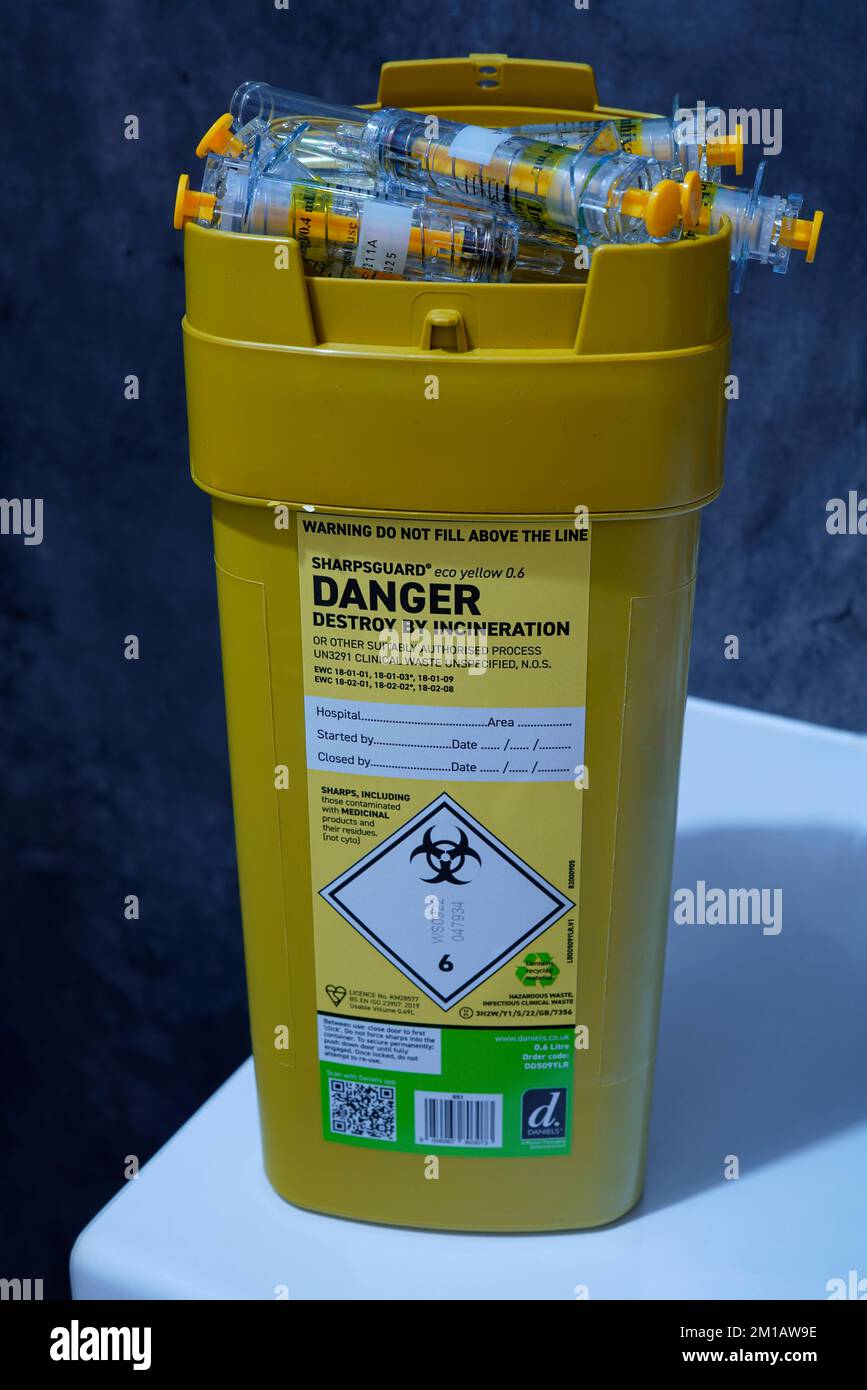Un conteneur de déchets médicaux à garde au corps avec seringues hypodermiques. Banque D'Images