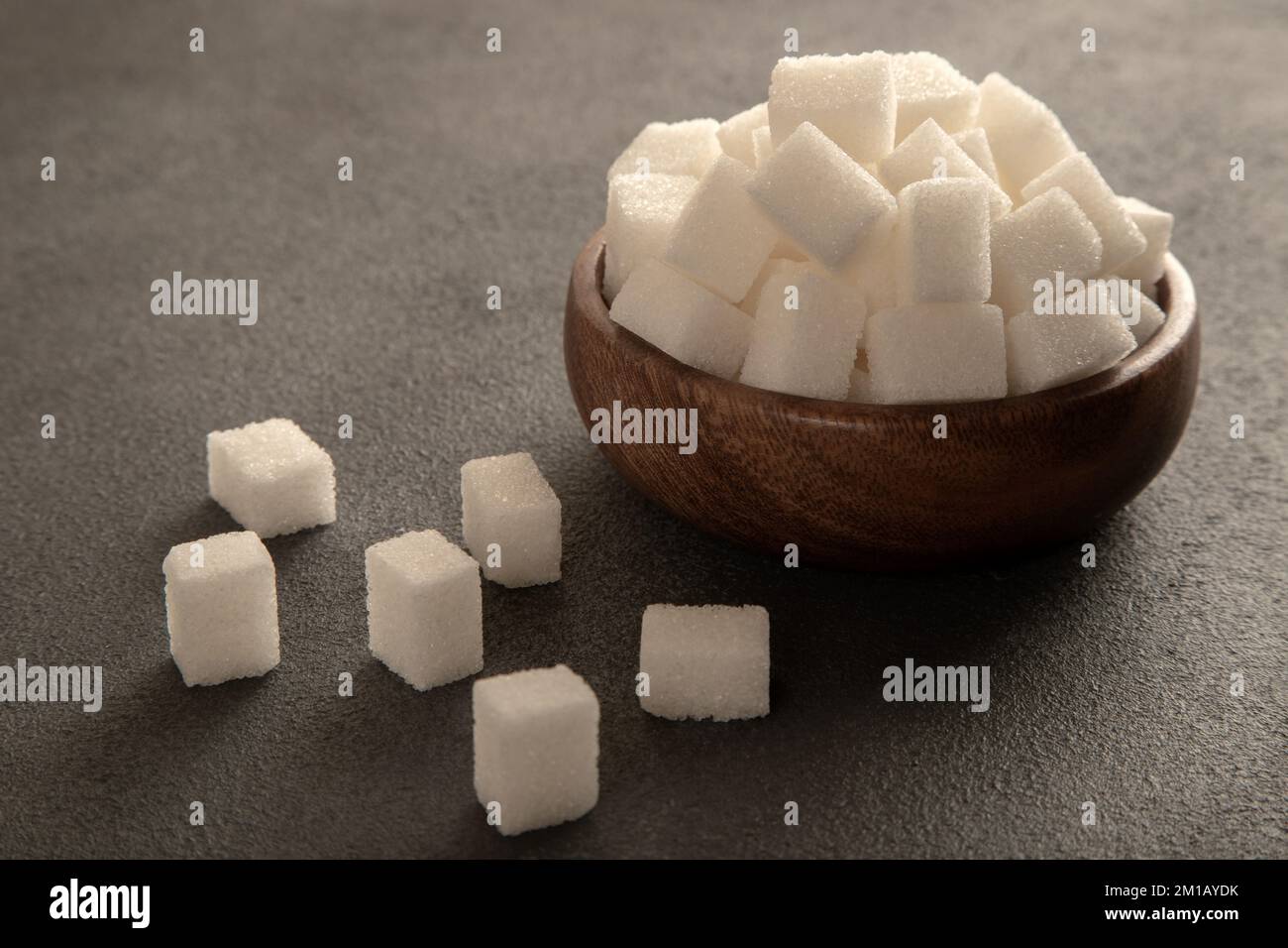 Sucre en cubes et sucre granulé sur fond sombre Banque D'Images