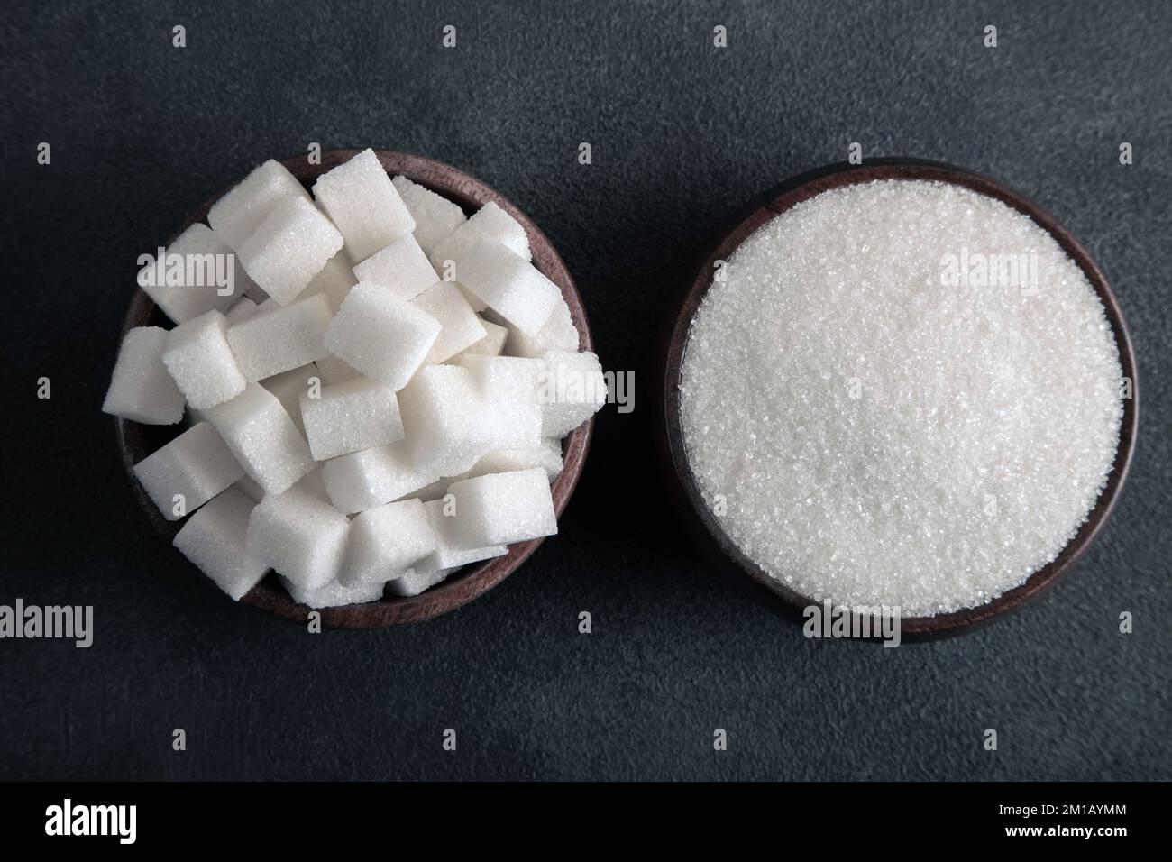 Sucre en cubes et sucre granulé sur fond sombre Banque D'Images