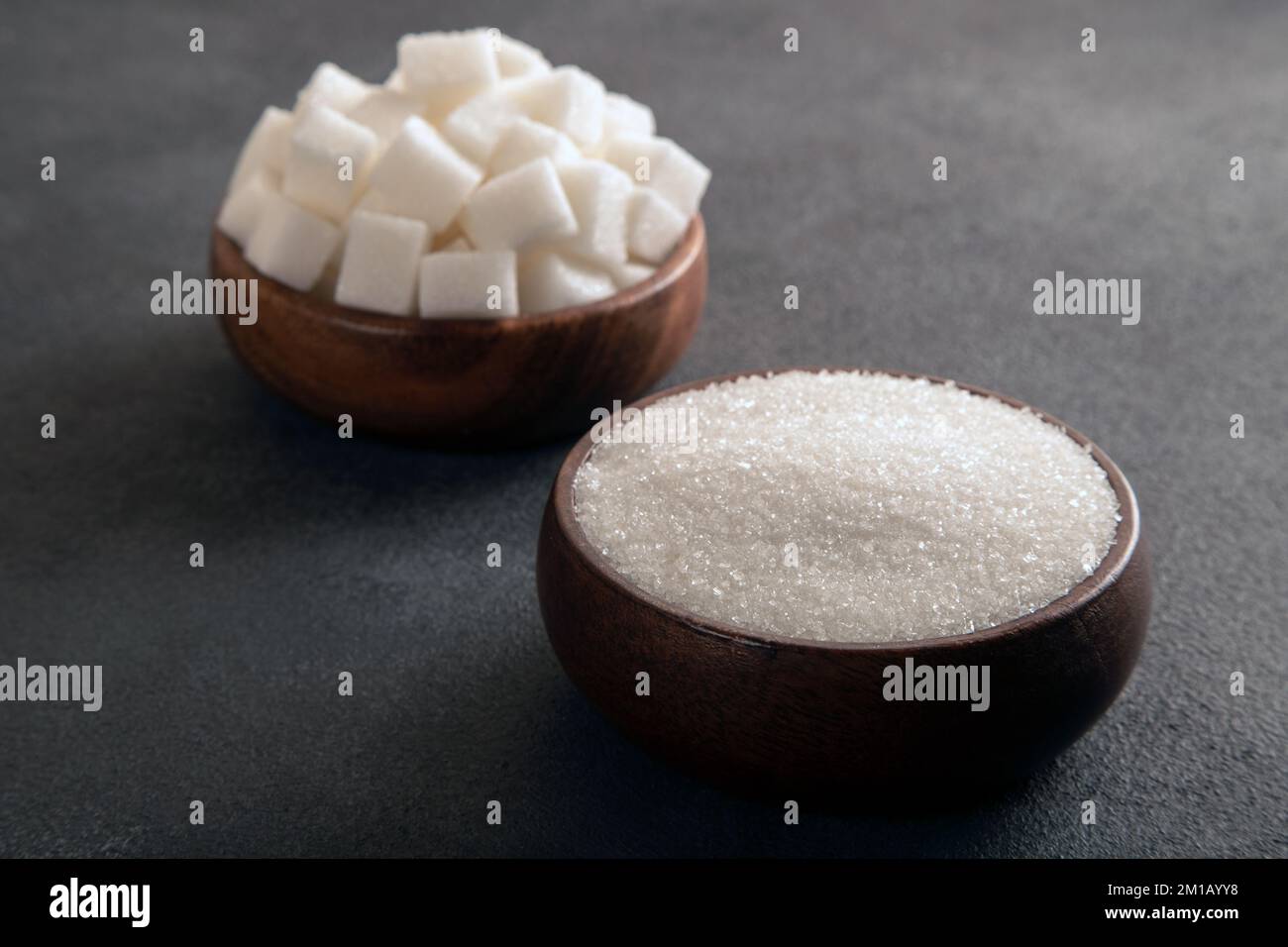 Sucre en cubes et sucre granulé sur fond sombre Banque D'Images