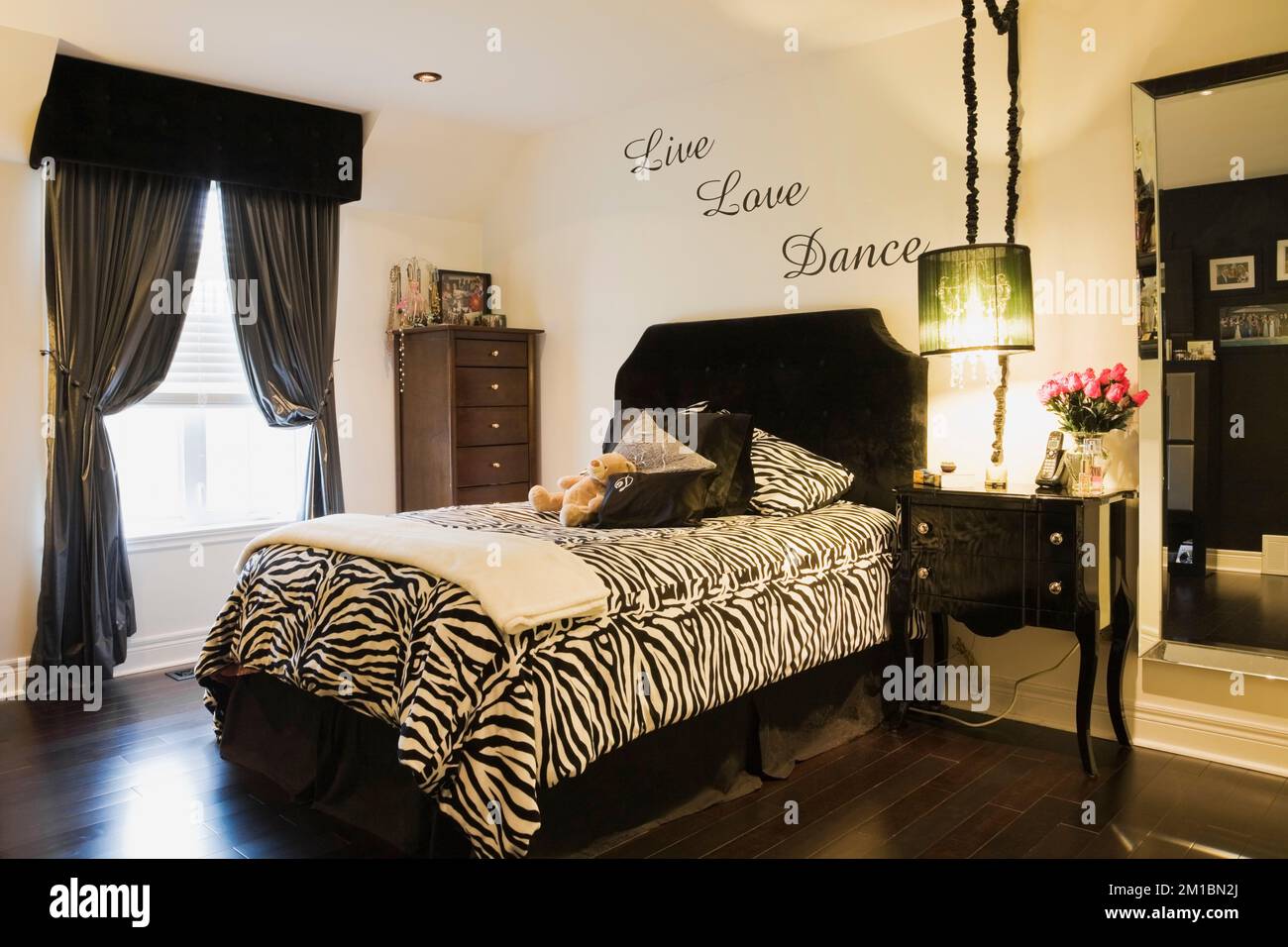 Lit simple avec zébrures et table de nuit dans la chambre de l'adolescent à l'intérieur d'une luxueuse maison. Banque D'Images