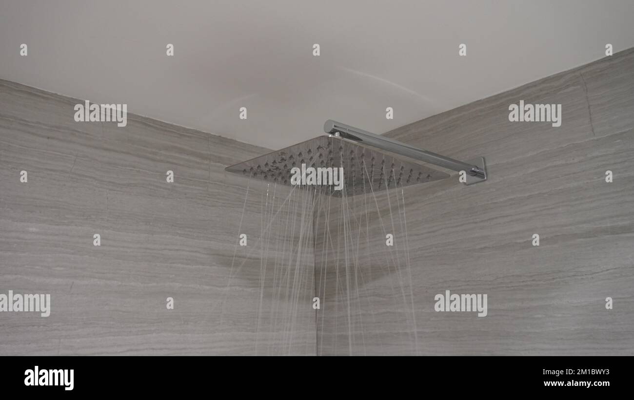 l'eau coule de la pomme de douche en acier inoxydable dans la salle de bains Banque D'Images