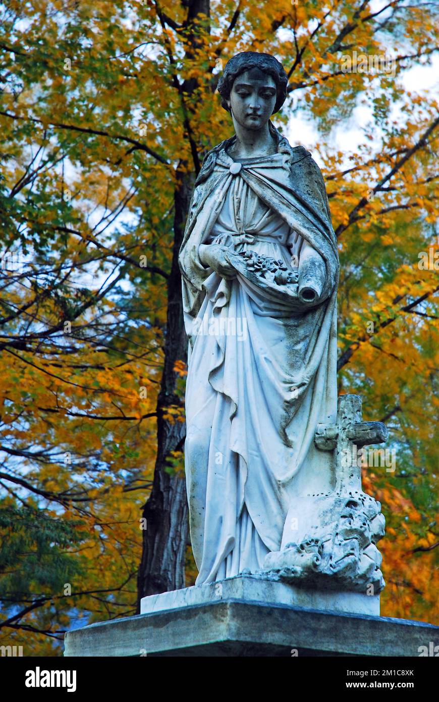 Une statue en marbre est encadrée de feuillage d'automne dans un cimetière du Vermont Banque D'Images