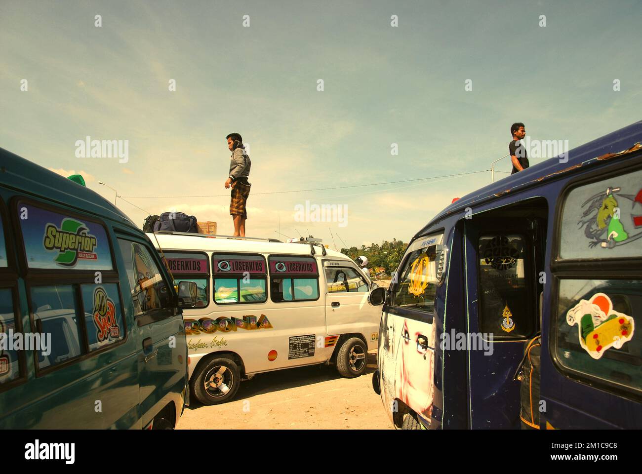 Les équipages des minibus se tenant sur le toit alors qu'ils attendent pour emballer les bagages des passagers, dans le port de ferry de Baa à Rote Island, Rote Ndao, East Nusa Tenggara, Indonésie. Selon Noah Kaiser (Mortenson Center in Global Engineering, Université du Colorado) et Christina K. Barstow (Bridges to Prosperity, Denver), dans leur document scientifique publié sur le développement durable le 14 février 2022, les infrastructures de transport rural constituent une composante essentielle du développement dans les communautés isolées des pays à revenu faible et moyen du monde entier. Accès via MDPI. Banque D'Images