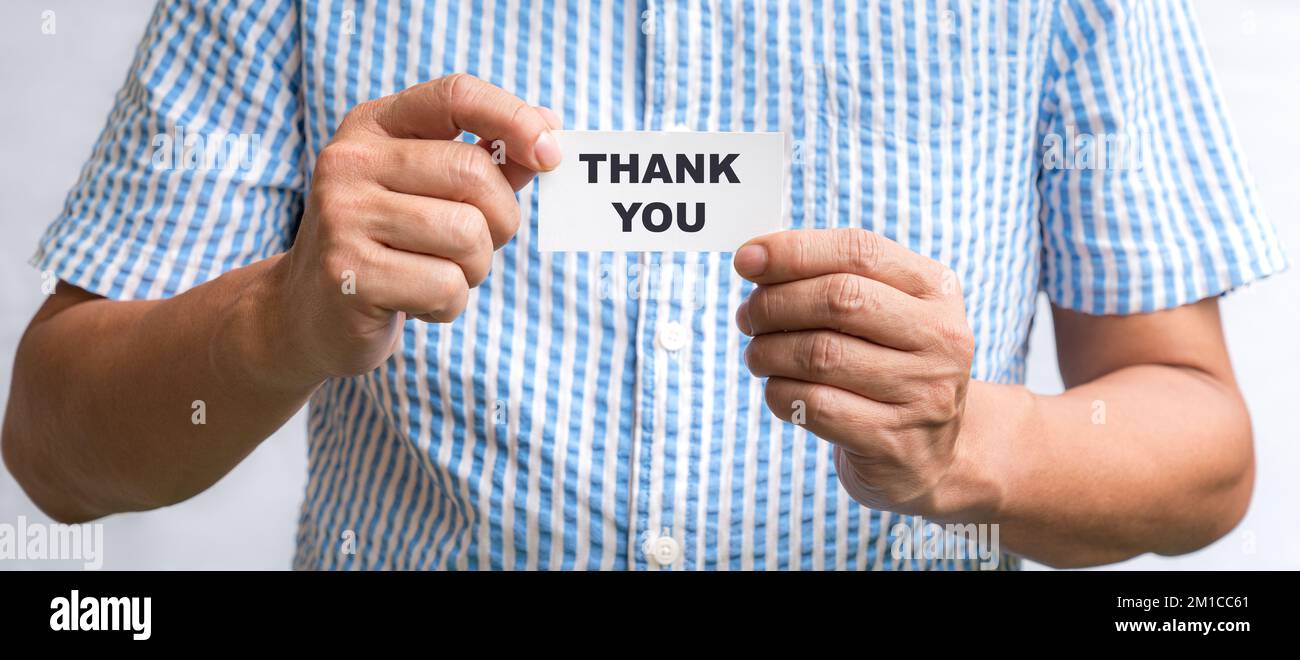 Homme tenant une carte de visite blanche avec des mots, Merci. Banque D'Images