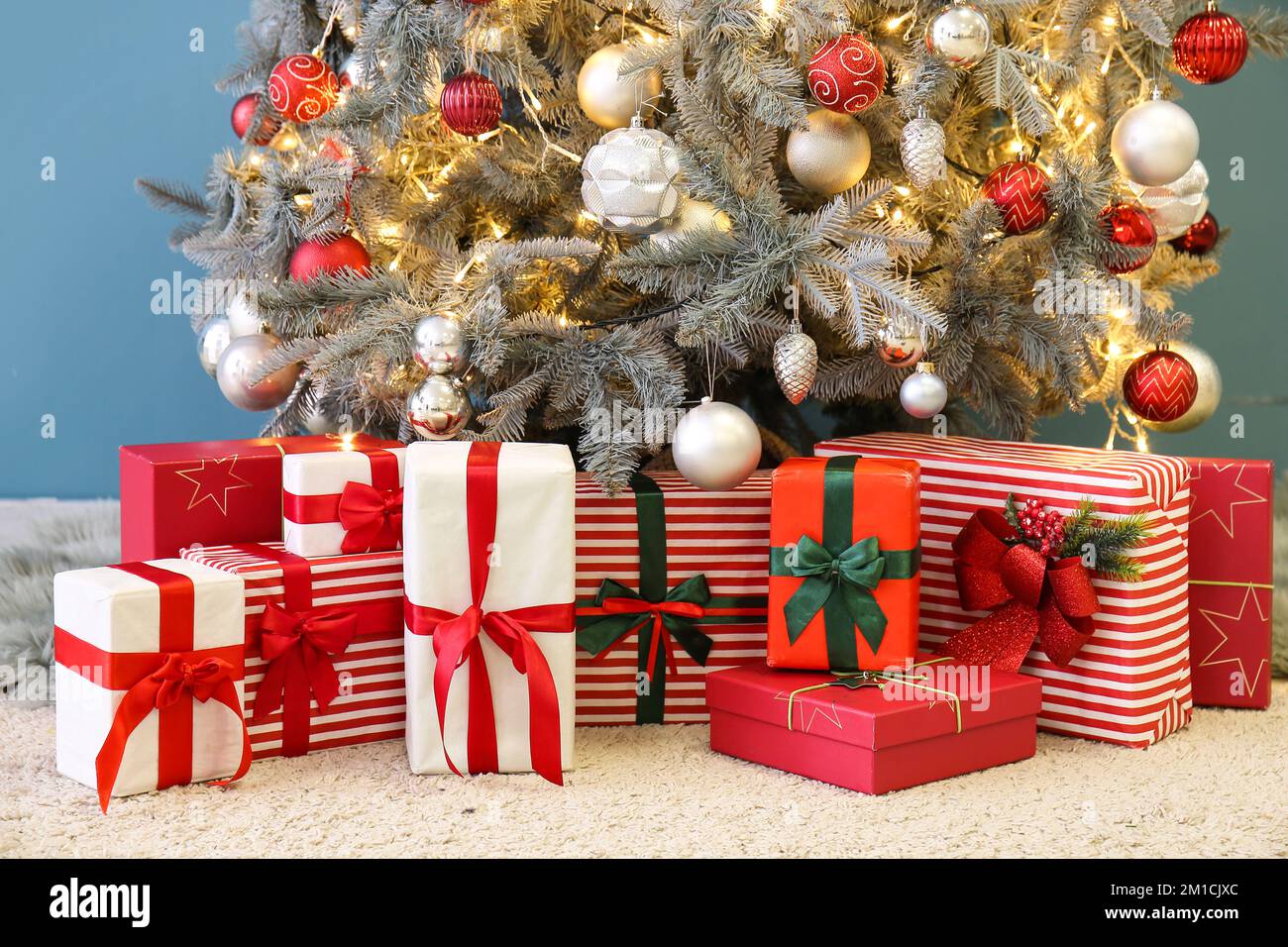 Cadeaux sous un sapin de Noël lumineux près du mur bleu Photo Stock - Alamy