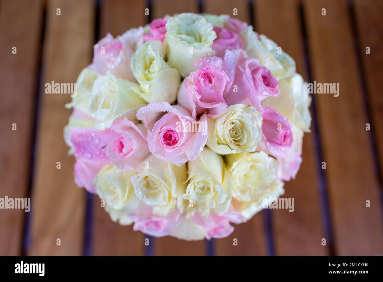 Un grand bouquet de roses dans un verre sur la table il y a des gouttelettes d'eau sur les pétales ont l'air frais et beau avec des fleurs roses et jaunes Banque D'Images