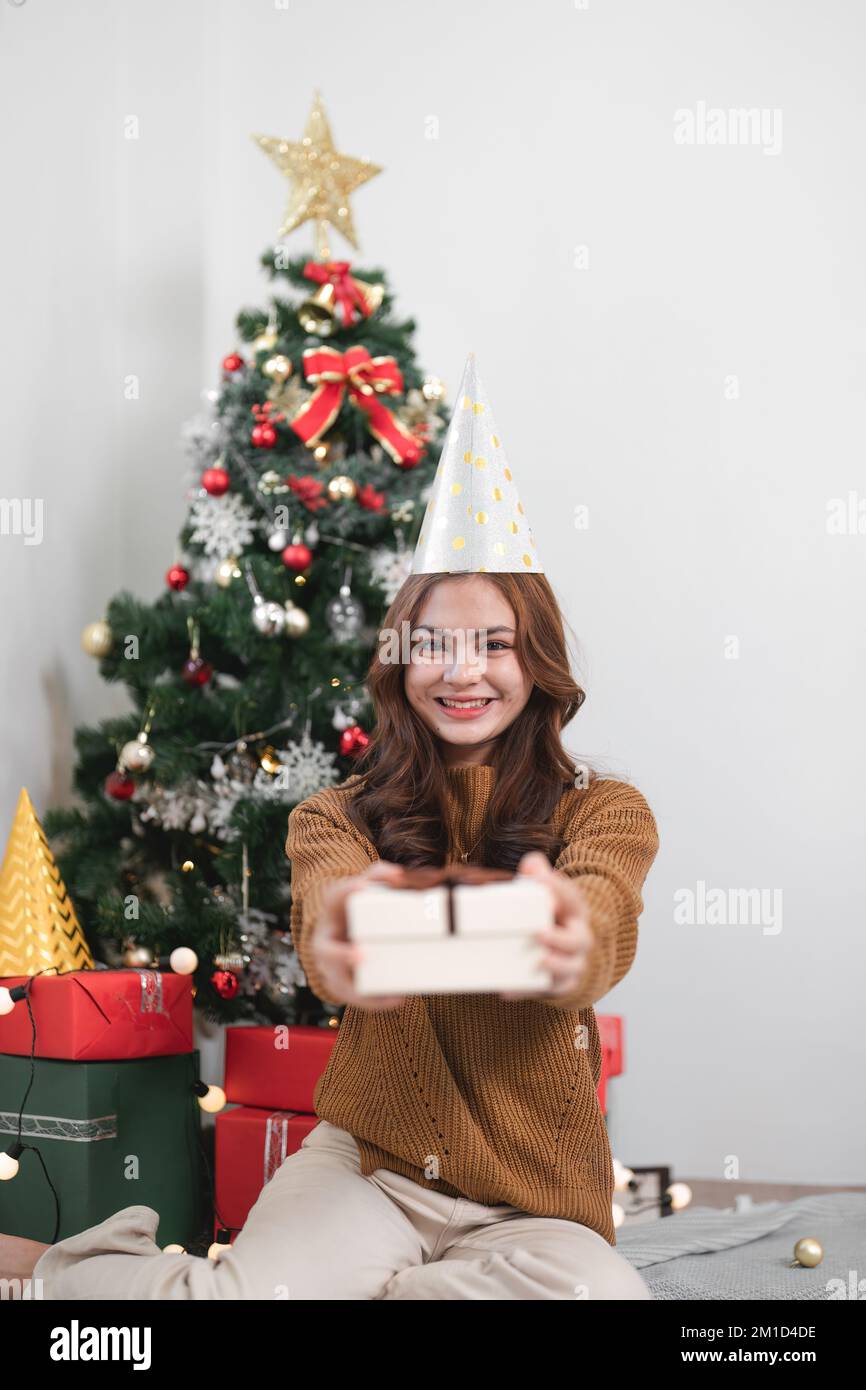 Portrait sourire fille tenir boîte cadeau s'asseoir sur le sol dans la maison à l'intérieur avec Noël décoration Banque D'Images
