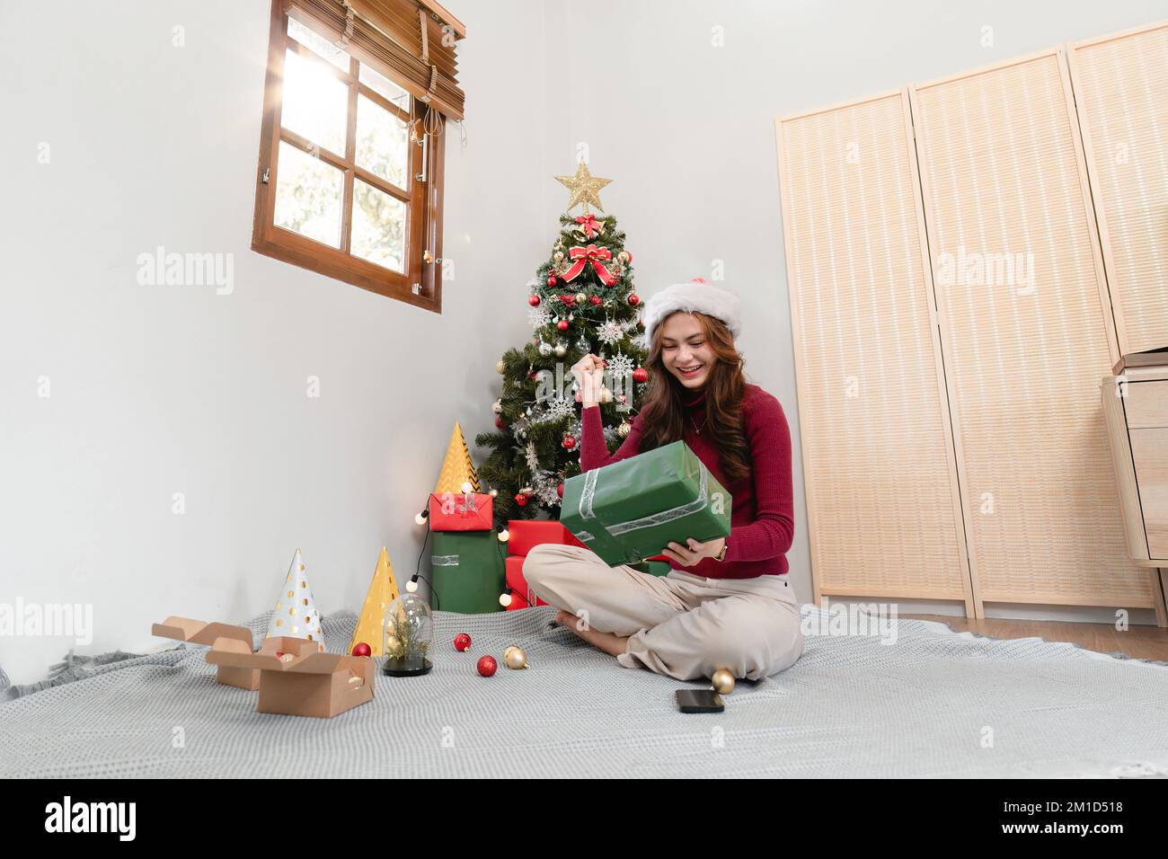 Bonne femme assise sur fond d'arbre de Noël. Une dame joyeuse surprise de la boîte cadeau. Mariez Noël et joyeuses fêtes Banque D'Images