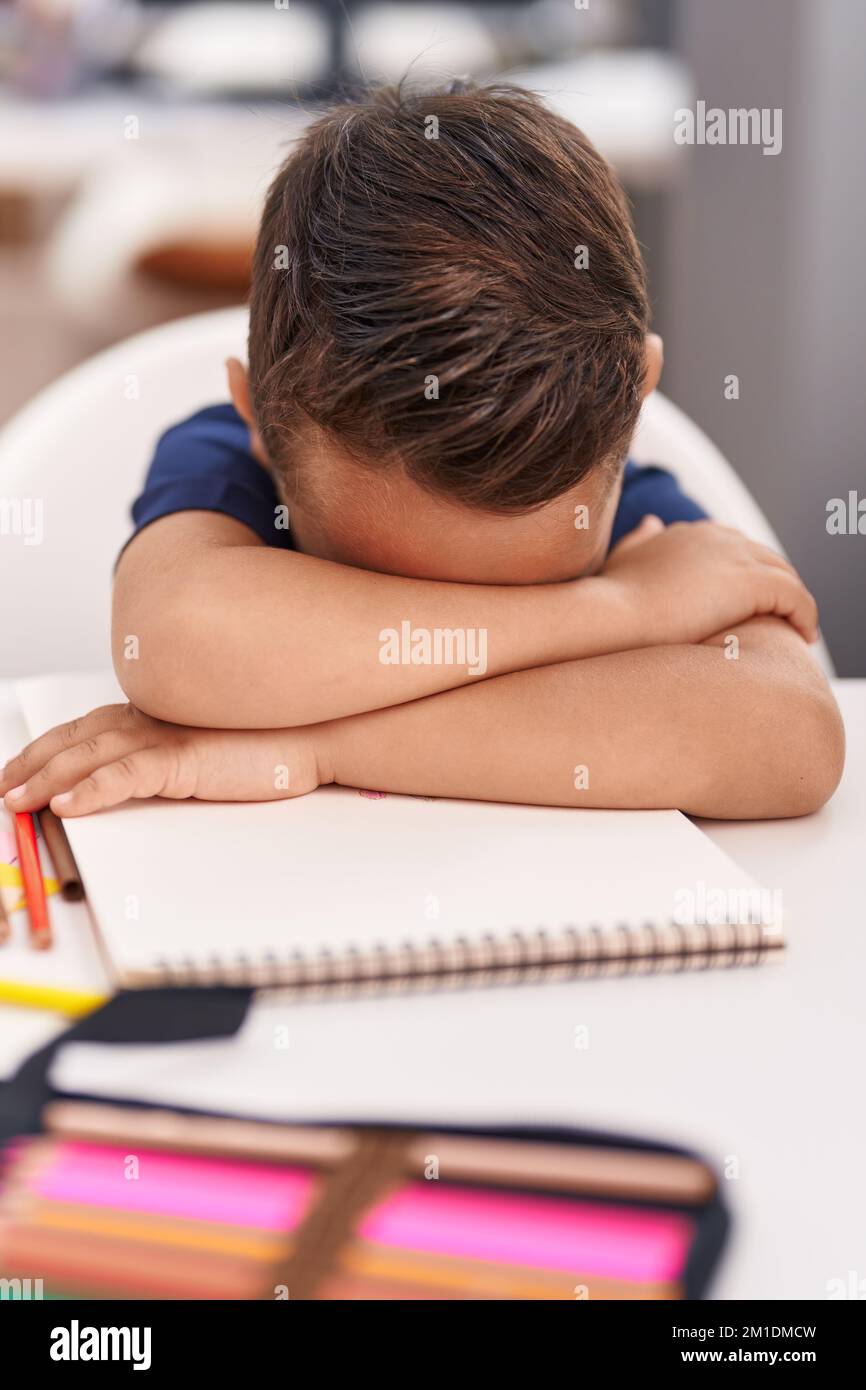 Adorable élève hispanique de tout-petit penchée sur un ordinateur portable qui pleure en classe Banque D'Images