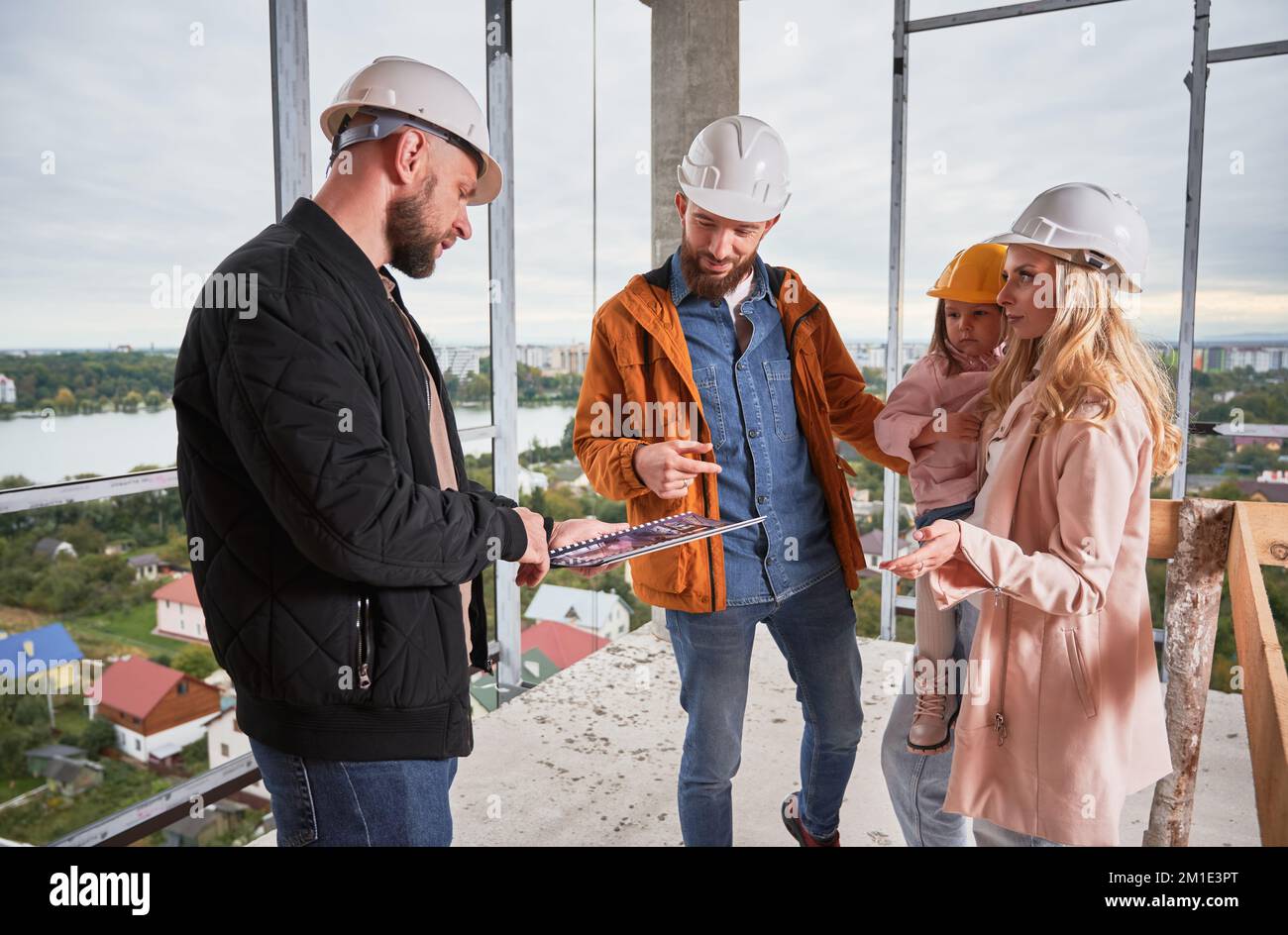 Homme et femme regardant le catalogue tout en choisissant le design d'intérieur pour un nouvel appartement avec ouvrier de bâtiment. Couple avec la planification de l'enfant construction de la maison et de la reconception avec le spécialiste. Banque D'Images