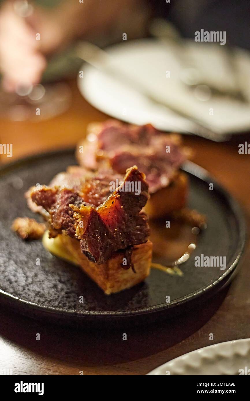 Joue de bœuf braise, jus de bœuf, oignon caramélisé, concentration sélective, cuisine savoureuse et savoureuse sur une assiette, plat exquis, concept de repas de restaurant créatif Banque D'Images