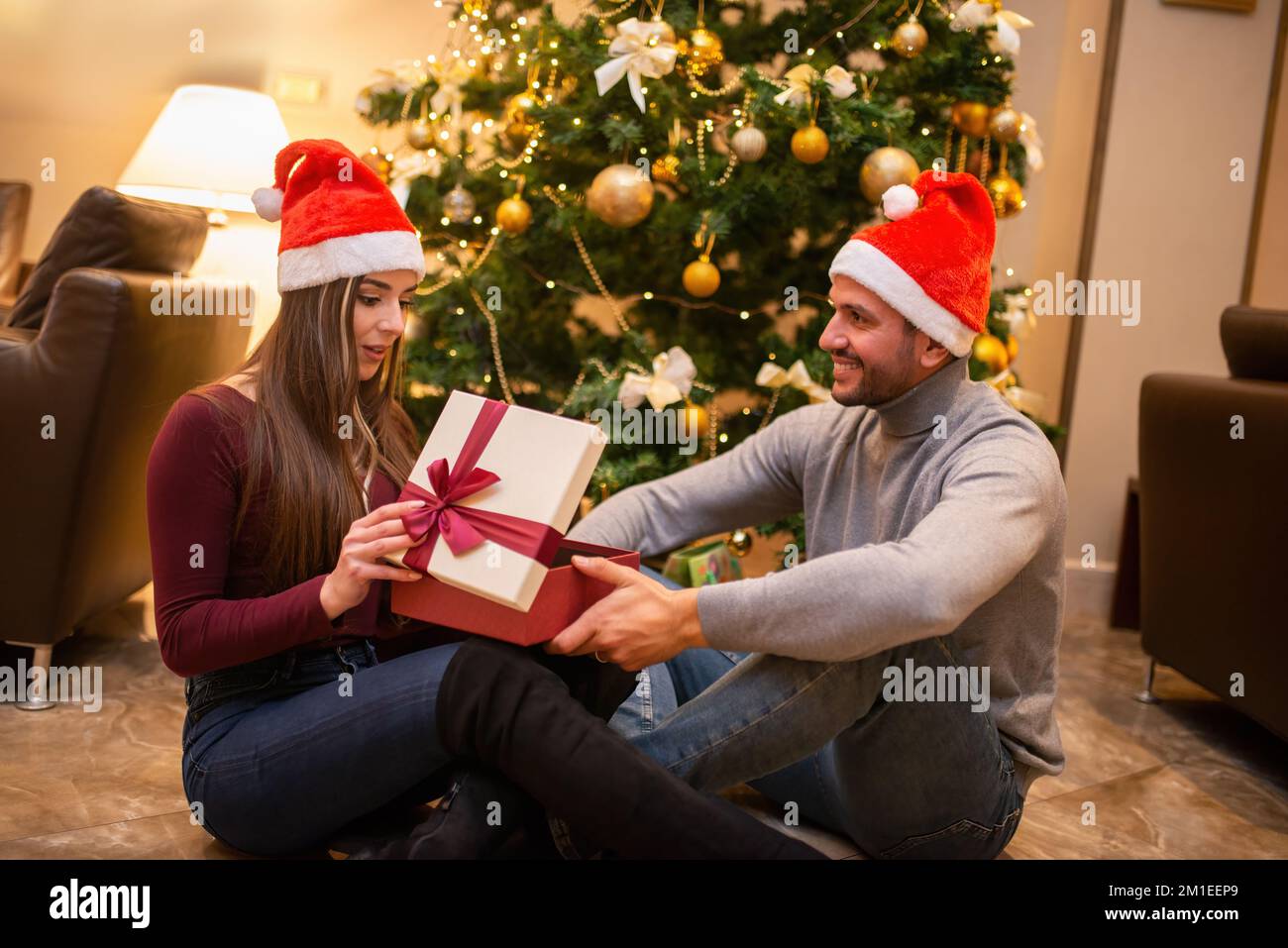 Jeune couple ouvrant un cadeau de Noël Photo Stock - Alamy