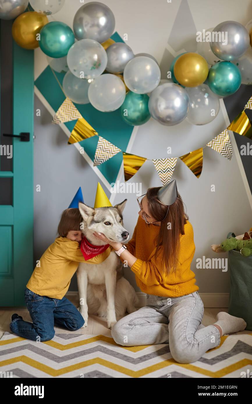 Chien animal anniversaire, famille mère et enfant câlin leur chien félicitant joyeux anniversaire Banque D'Images