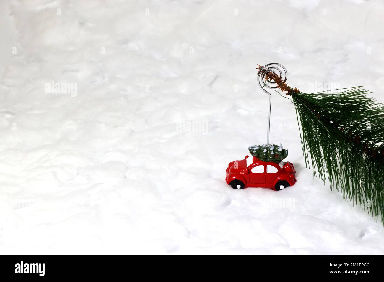 Voiture tirant un arbre de Noël dans la neige, concept de vacances créatif, design artistique minimal Banque D'Images