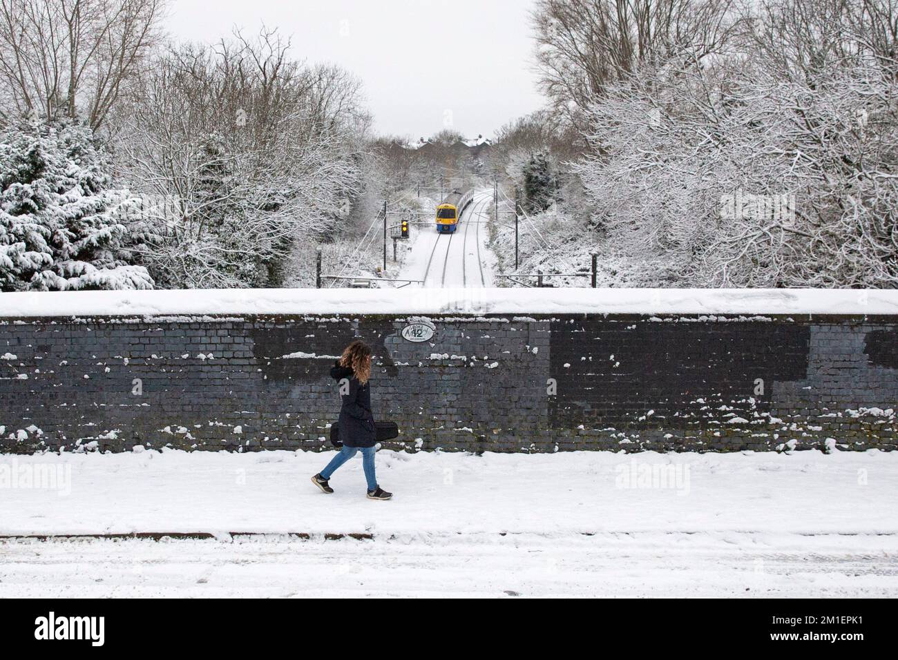 Londres , Royaume-Uni . Une personne traverse un pont de chemin de fer rempli de neige à Queens Park, les navetteurs de l'ouest de Londres à travers Londres font face à un défi pour ge Banque D'Images