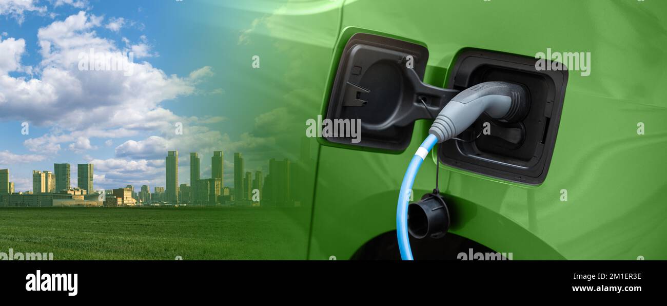 Gros plan d'une voiture électrique avec un câble de recharge et une ville verte. Concept de transport propre Banque D'Images
