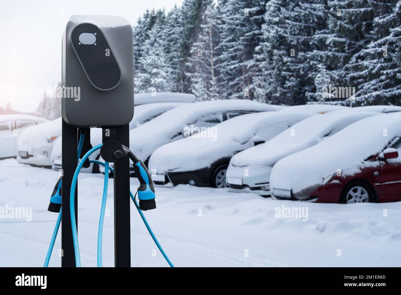 Station de charge de voiture électrique sur fond de voitures d'hiver enneigées Banque D'Images