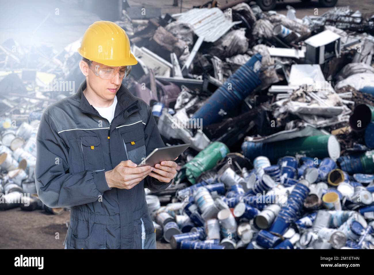 Un employé avec une tablette numérique dans une usine de recyclage des déchets. Concept de gestion des déchets Banque D'Images