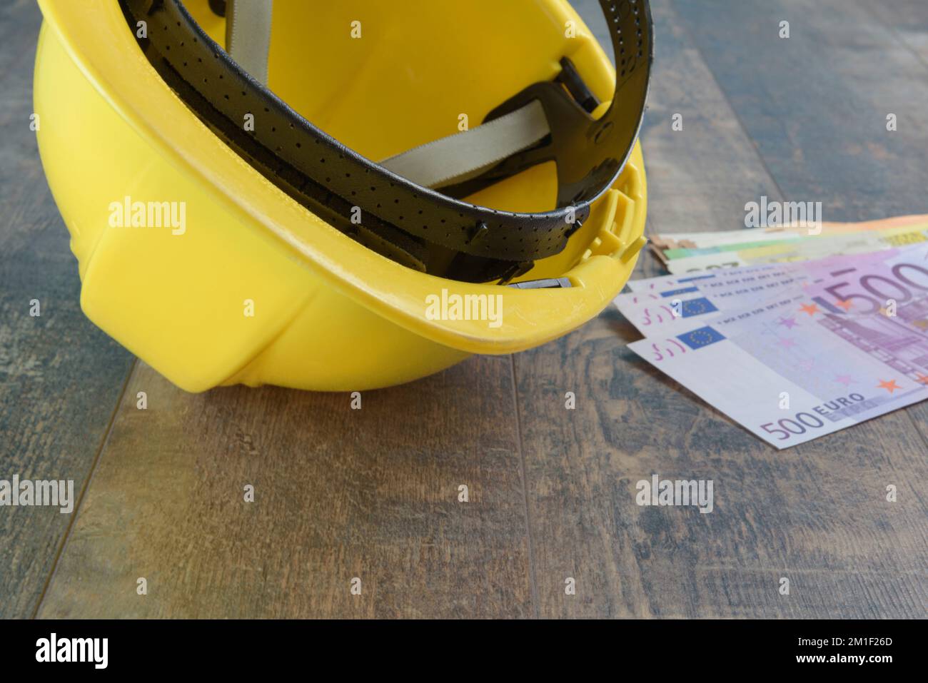 Casque de construction jaune et billets en euros en espèces. Investissement dans le budget de la construction. Banque D'Images