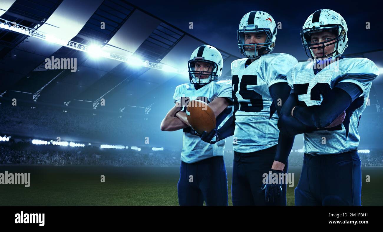 Coéquipiers. Trois athlètes américains de football, des sportifs debout en uniforme isolés au stade avec des flashs. Concept de sport, défis Banque D'Images