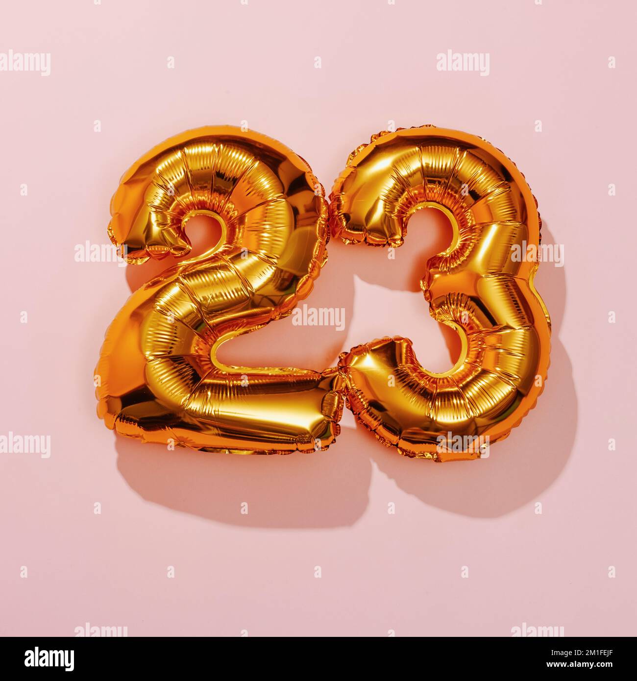deux ballons dorés en forme de numéro formant le numéro 23 sur fond rose Banque D'Images
