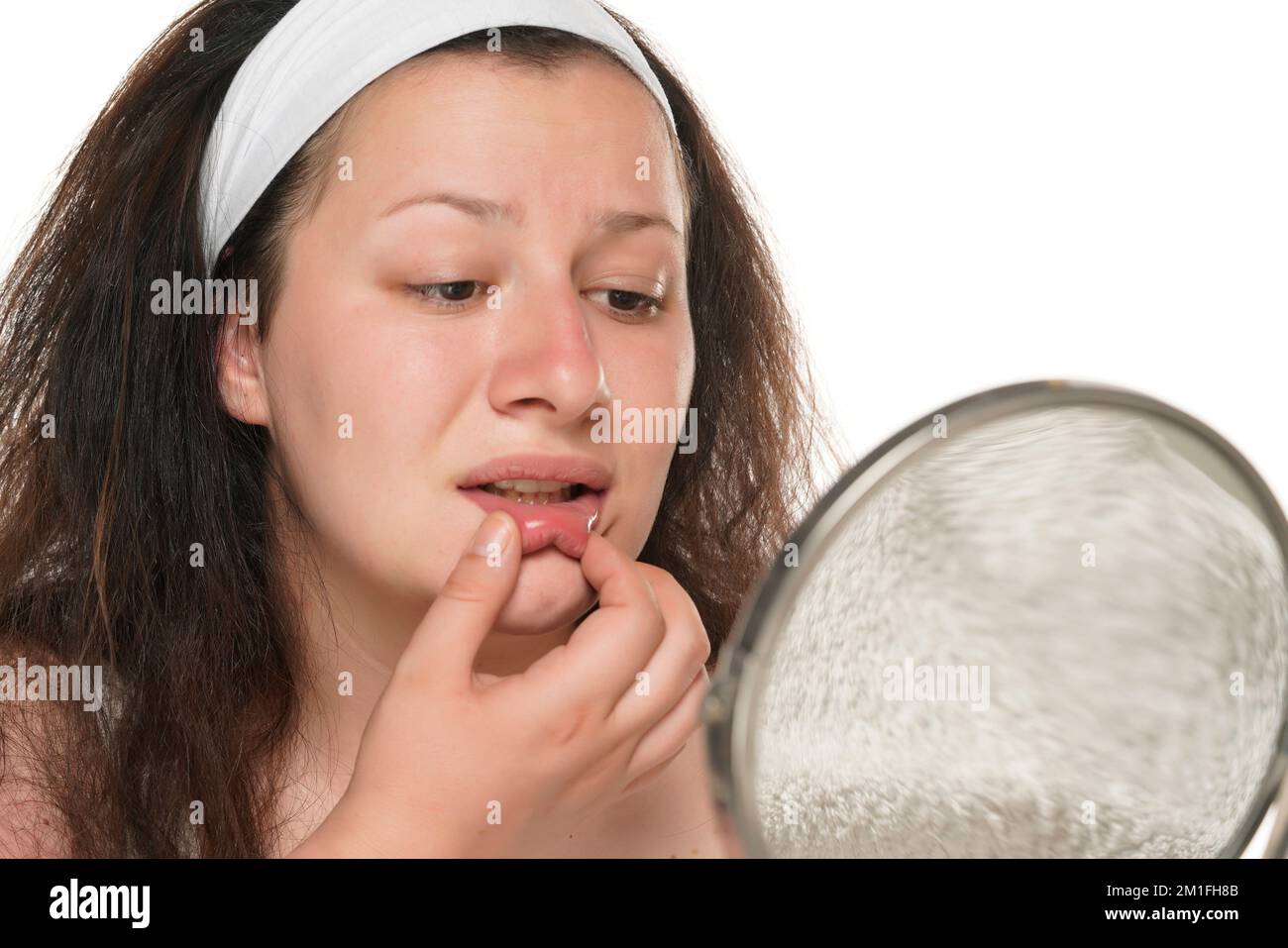 La jeune femme chubby vérifie sa bouche dans le miroir. Banque D'Images